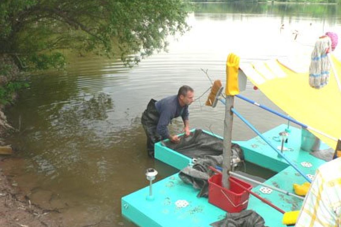 Man launching a bright blue boat in the lake.