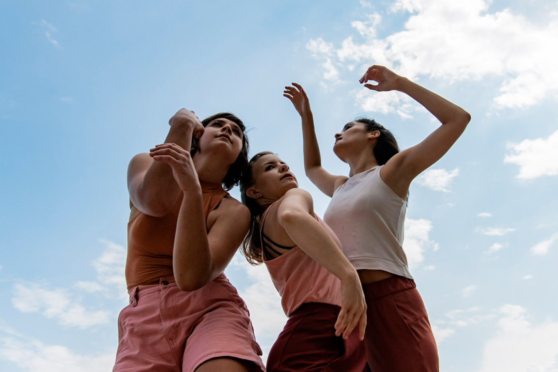 Three people stand against a blue sky background 