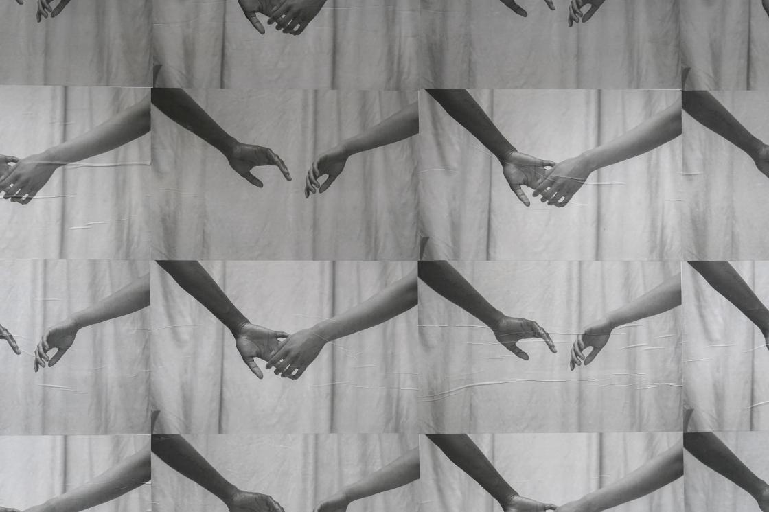 The image is a wheatpaste installation called "Connection" by the artist Cruz. The work is a series of photos printed in greyscale on poster paper. The photos depict a pair of arms reaching out for an embrace, with each poster representing a new progression of the motion.