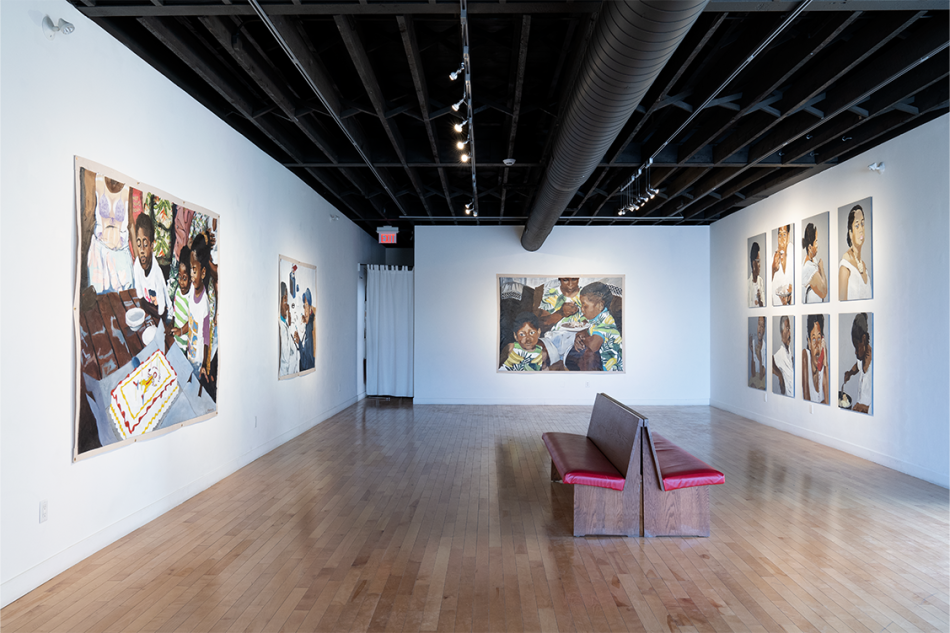 large room with paintings mounted on 3 walls with two red benches in the middle on the room