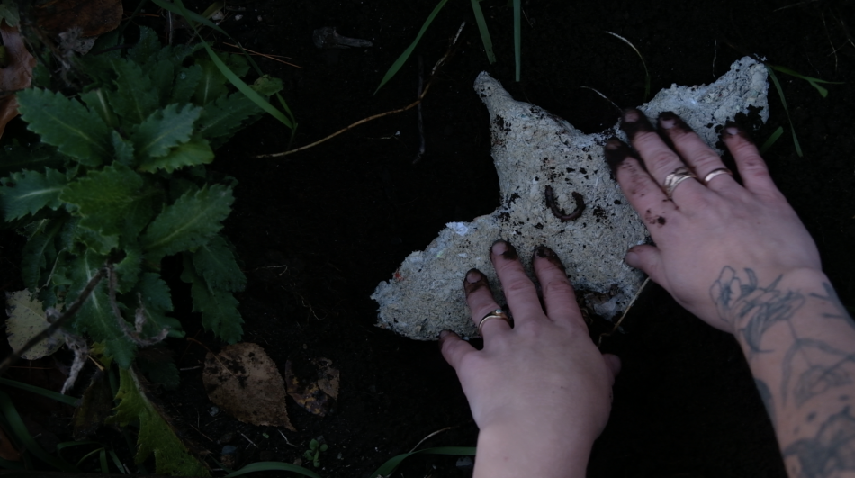 One of Abby's paper-pulp, seed-infused pieces being planted in the soil.