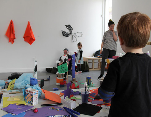 Another photo that shows the city and its surroundings from the top of the table. In the foreground, there is a child with short brown hair who appears to be white. We see this child from behind, as if they are also looking at the city below them.